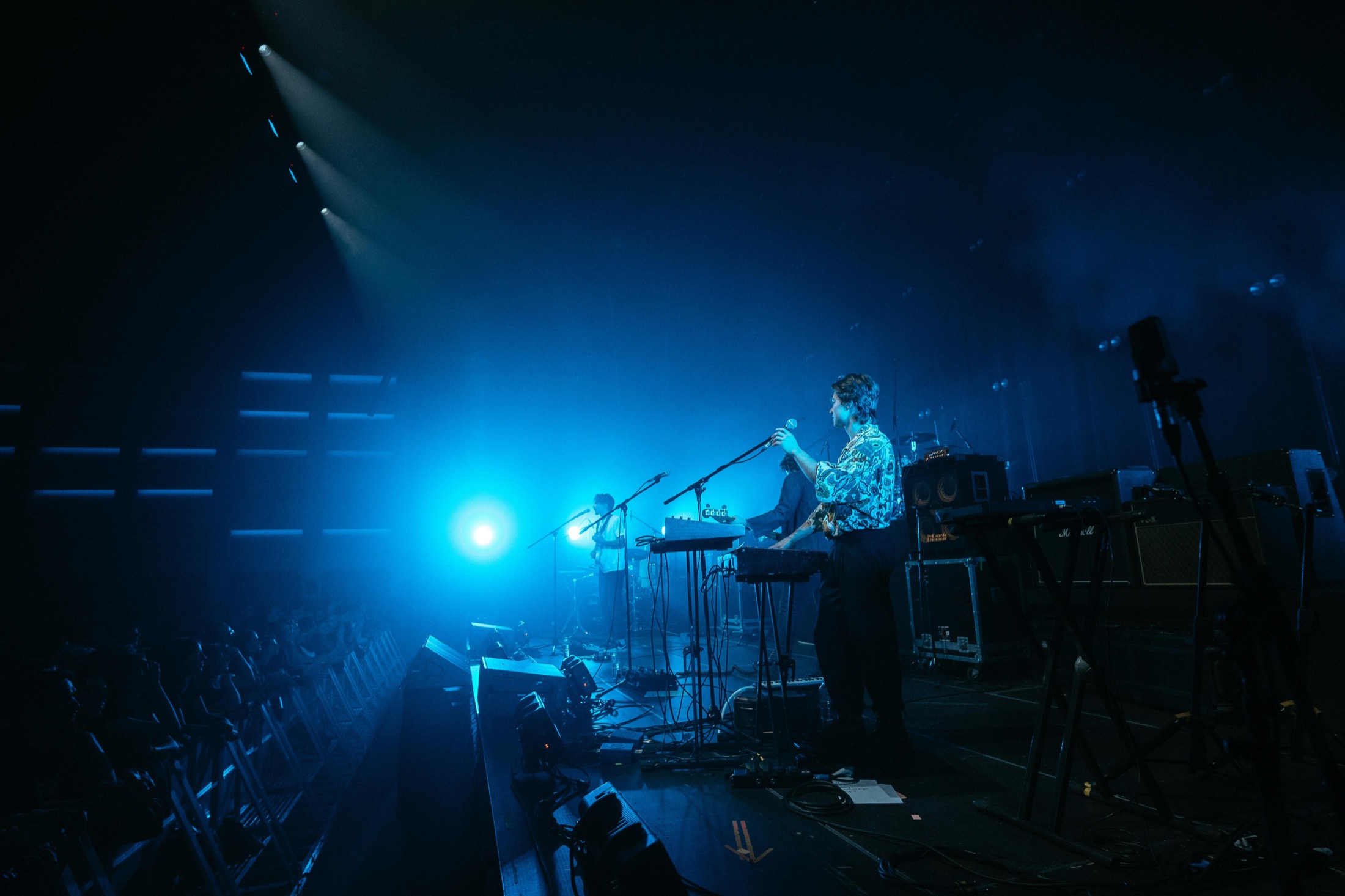 Musicians performing on a blue-lit live concert stage Musicians performing live on a blue-lit concert stage in front of an audience